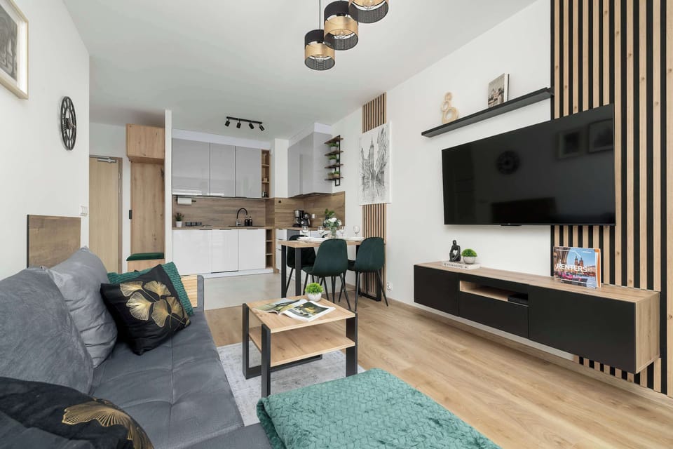 The open-plan space connects the living room and kitchen, featuring a dining table with trendy green velvet chairs.