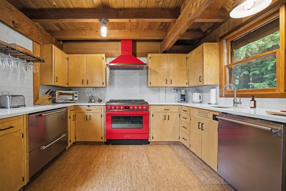 Designer alpine kitchen with luxury red range & handcrafted wood cabinetry.