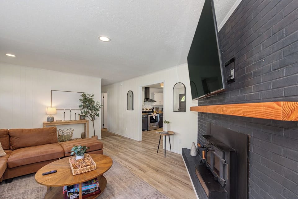 Unwind in your open-plan living space with a cozy fireplace, comfortable seating, and modern kitchen—perfect for relaxing evenings together.