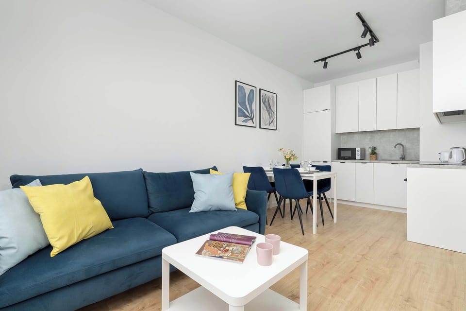 A wide shot captures the entire living and dining space, showcasing the consistent use of blue, yellow, and white tones. The overhead track lighting provides a contemporary industrial feel to the room.