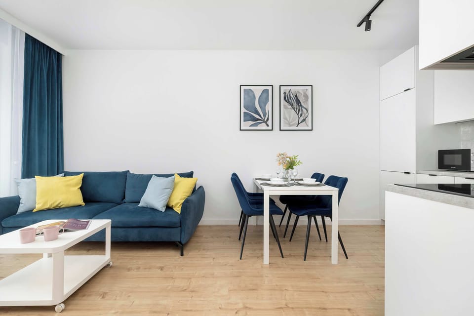 The open-plan living area shows a seamless transition between the lounge and a small dining nook. Two minimalist line art pieces decorate the wall above the dining table, adding a sophisticated touch.