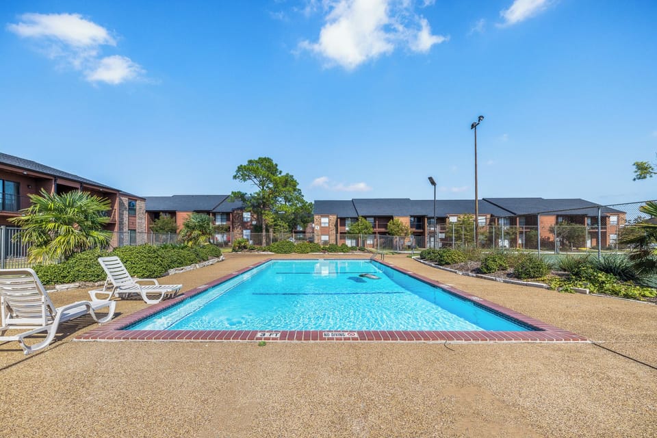 Sunny outdoor pool with lounge chairs and spacious sundeck