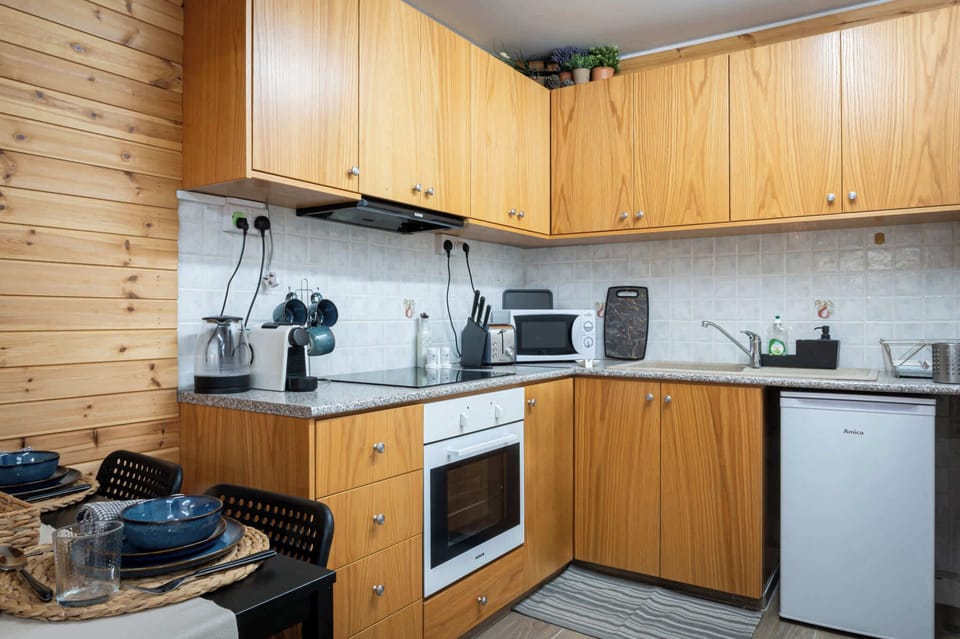 A well-organized kitchen combines modern functionality with an inviting atmosphere. This space features warm wood cabinetry, a built-in oven, microwave, and fridge. With a dining nook for four, it is perfect for a quick coffee or a quiet dinner.