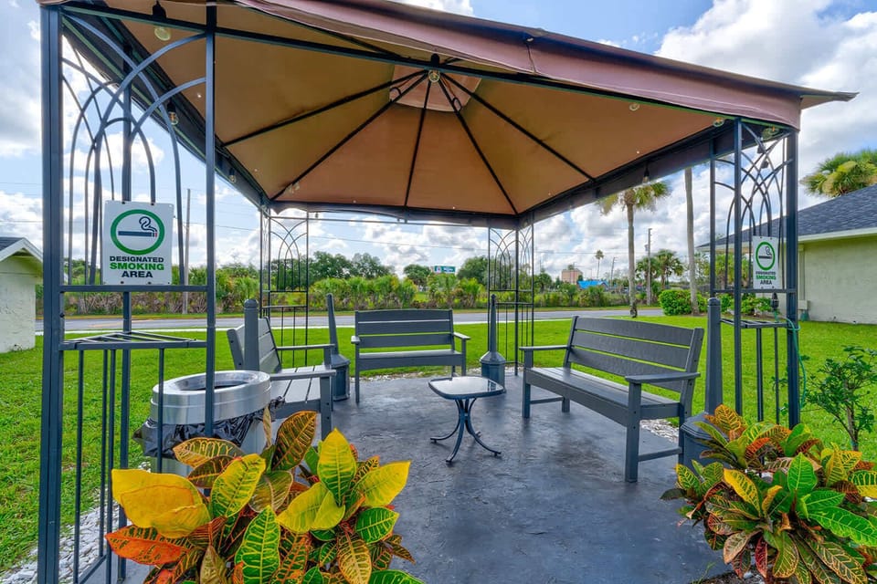 Covered outdoor seating area designated for smoking with benches and a small table.