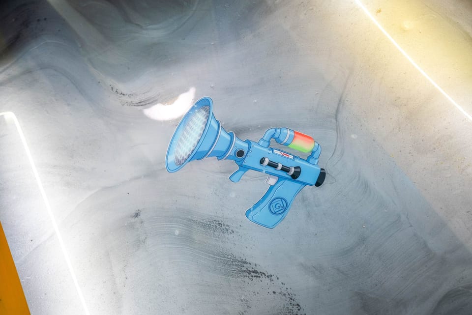 A close-up of a blue toy ray gun on a textured surface with soft lighting.