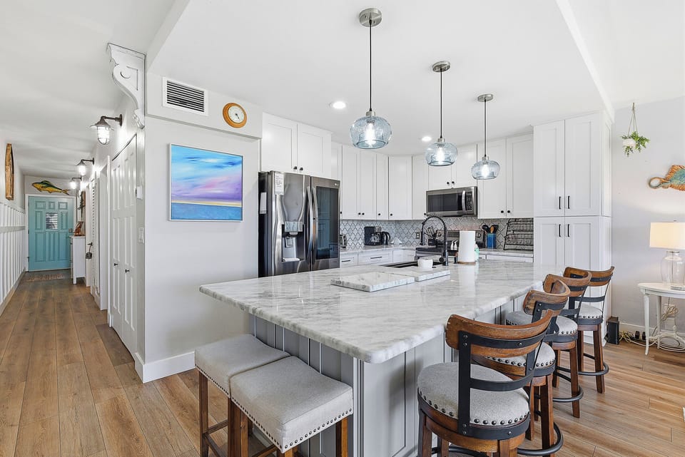 Gather in this bright beach stay kitchen featuring a spacious island, bar seating, and modern finishes. Perfect for meals, drinks, and easy coastal living after a sun-filled day at the beach.