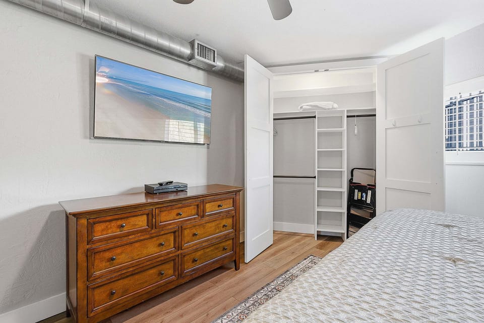 Enjoy a comfortable beach stay in this inviting bedroom featuring coastal décor, ample storage, and a spacious closet. A relaxing retreat to settle in and unwind after a day by the beach.