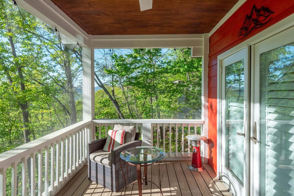 Screened porch with a ceiling fan and partial mountain views.