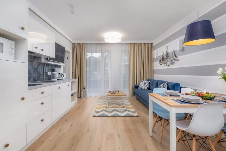 A spacious living room seamlessly connected to an open kitchen. The area is tastefully decorated with a modern aesthetic.