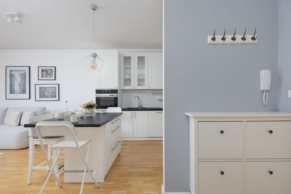 A hallway with a chest of drawers and soft blue walls. Decorative elements and lighting create a welcoming entrance.