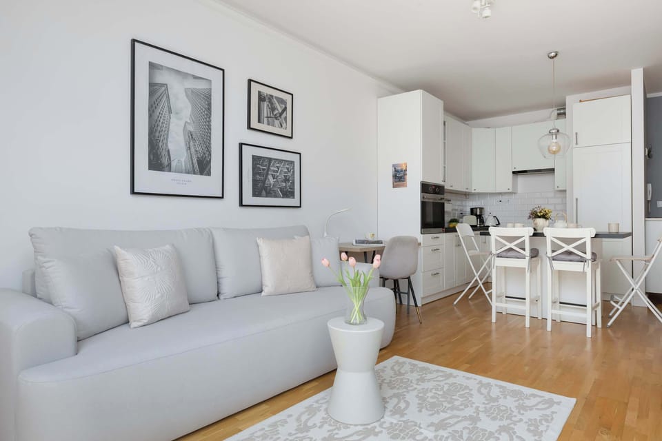 A compact living room with a sofa placed against the wall and a dining table nearby. Subtle decorations and neutral colors make the space feel inviting.
