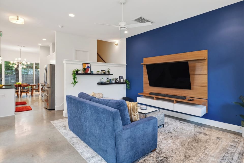 Stylish living area with a bold accent wall, mounted TV, and comfortable seating for movie nights and lounging.