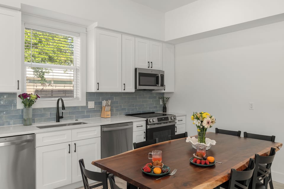 Gourmet kitchen featuring white cabinetry, stainless steel appliances, and dining table.