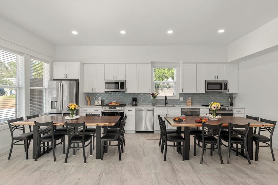 Bright, open-concept kitchen and dining area with dual dining tables for large groups