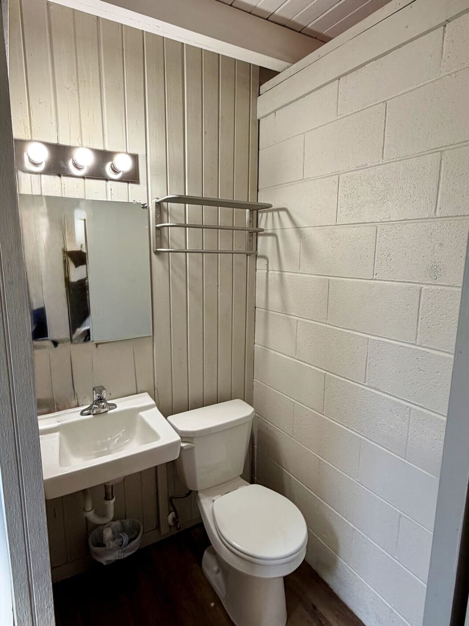 Bathroom featuring a pedestal sink, toilet, towel rack with fresh linens, and mirror in The Vinyl Lounge at The Cedar