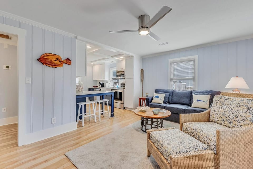 Relax in your coastal living space with beach-themed decor and open layout flowing to the modern kitchen.