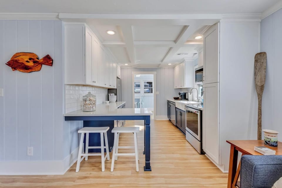 Your fully equipped galley kitchen features modern appliances, a breakfast bar with stools, and coastal-inspired décor for memorable meal preparation.