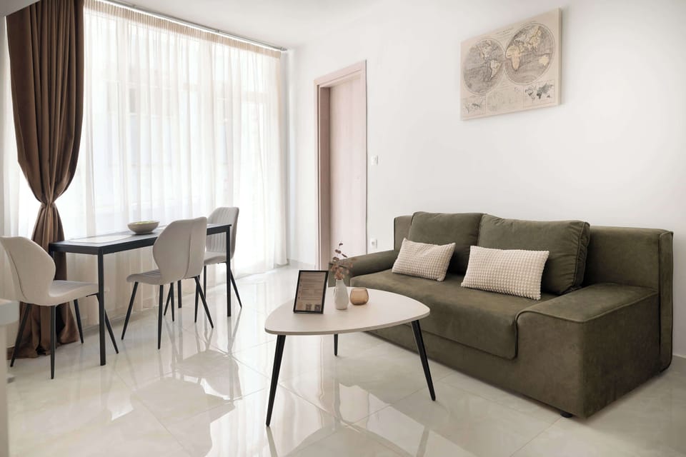Living room & dining area
Bright living room with a green sofa, round coffee table, and dining area beside large sheer-curtain windows. The open layout and natural light create a relaxed, airy space.
