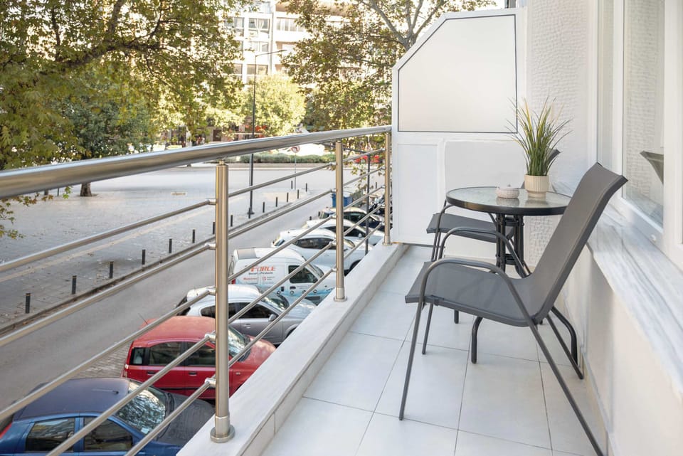 Private balcony with two outdoor chairs and a small table, overlooking the street. A simple, bright space ideal for sitting outside and enjoying fresh air.
