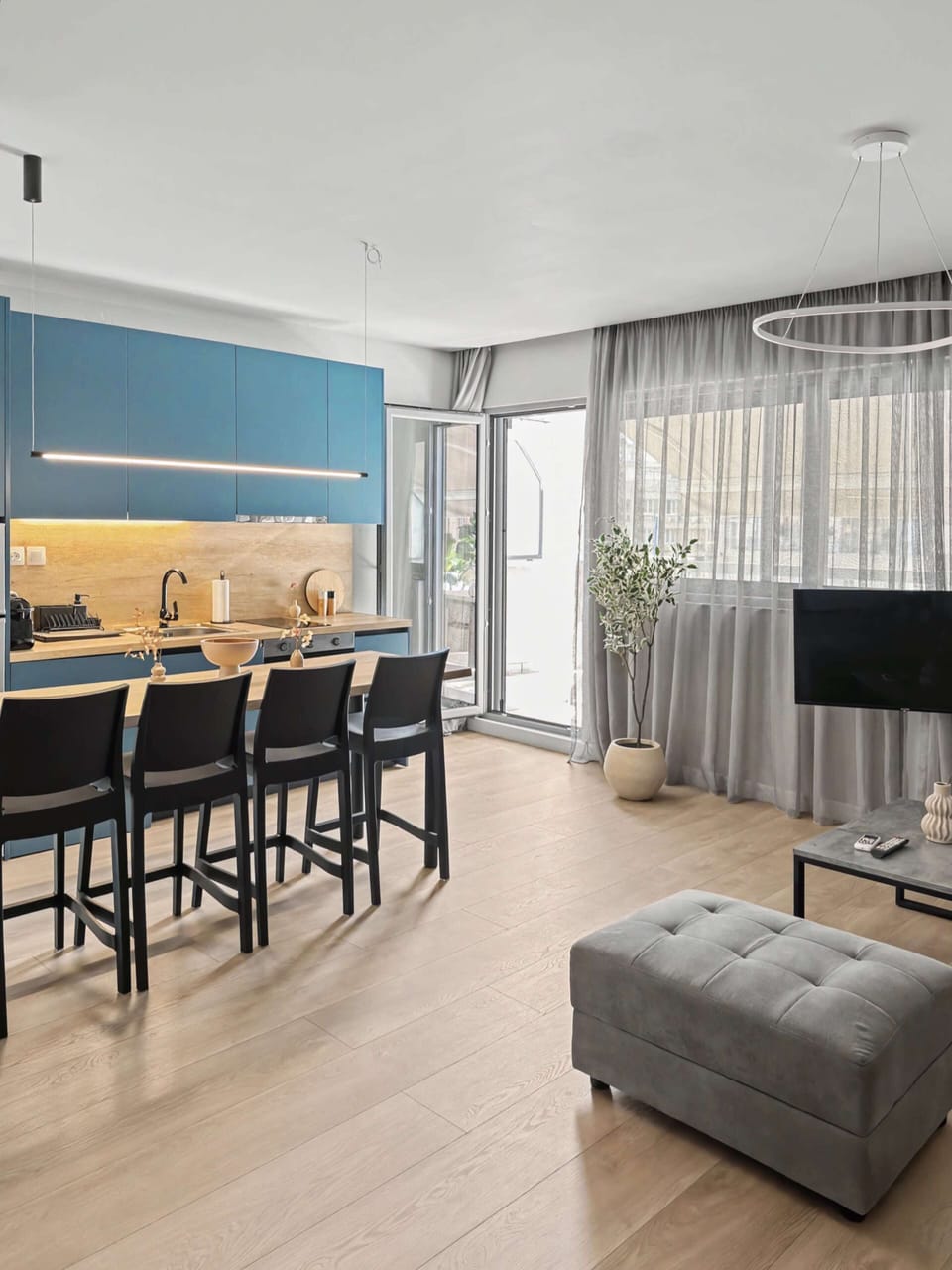 Living room
Unwind in the modern, light-filled living room. Features a plush sectional, a large-screen TV, and easy access to a private balcony via glass doors.