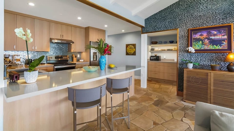 Your modern kitchen features sleek countertops, tropical flowers, and warm wood accents creating the perfect space for preparing island-inspired meals.