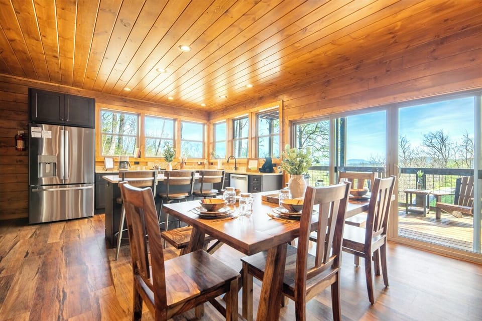 Your open-concept dining room flows seamlessly into the kitchen, where warm wood tones and panoramic windows create the perfect space for memorable meals.