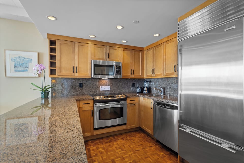 Your fully equipped kitchen features granite countertops, stainless steel appliances, and warm wood cabinetry for preparing memorable meals together.