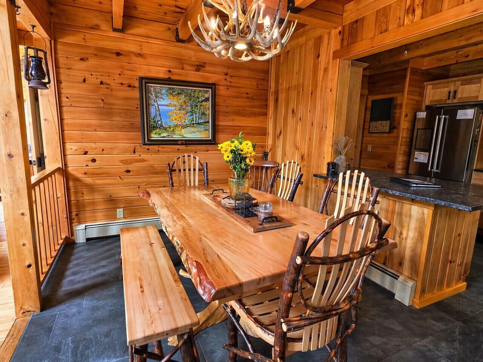 Rustic log cabin dining room with handcrafted wood furniture, warm lighting, and cozy lodge charm.