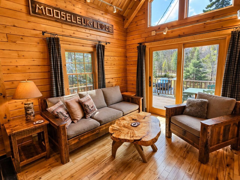 Cozy log cabin living room with soaring ceilings, rustic wood interiors, and peaceful forest views.
