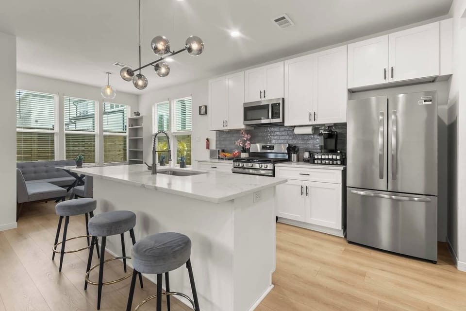 Modern kitchen with stainless steel appliances, island seating, and a Keurig coffee maker.