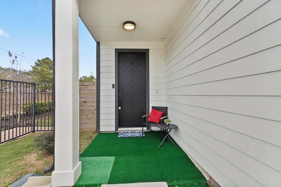 A covered front porch with a private entrance, seating area, and a small table, perfect for enjoying a quiet moment outdoors.