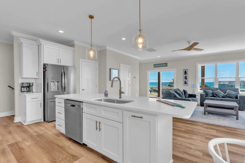 Cook while enjoying stunning ocean views through your expansive windows in this bright, modern kitchen with pristine white cabinetry and stainless steel appliances.