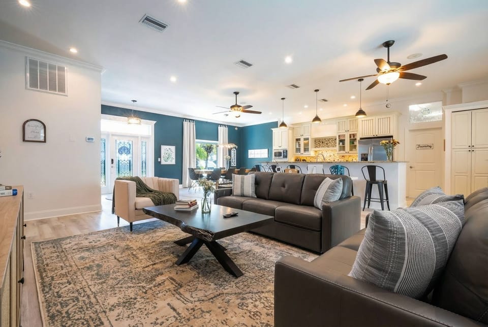 Welcome to a beautifully designed living area with soft gray sofas and a chic coffee table that invite relaxation. A bright blue accent wall enhances the airy feel, while natural light pours in, creating an uplifting atmosphere.