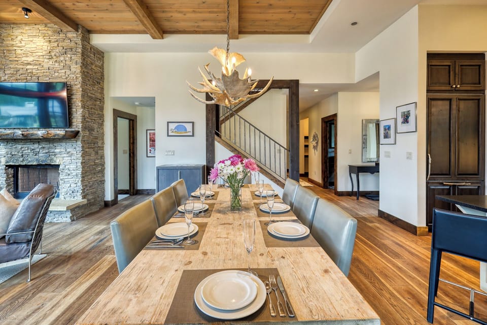 Gather around this elegant dining table where rustic wood meets modern comfort under a stunning antler chandelier.