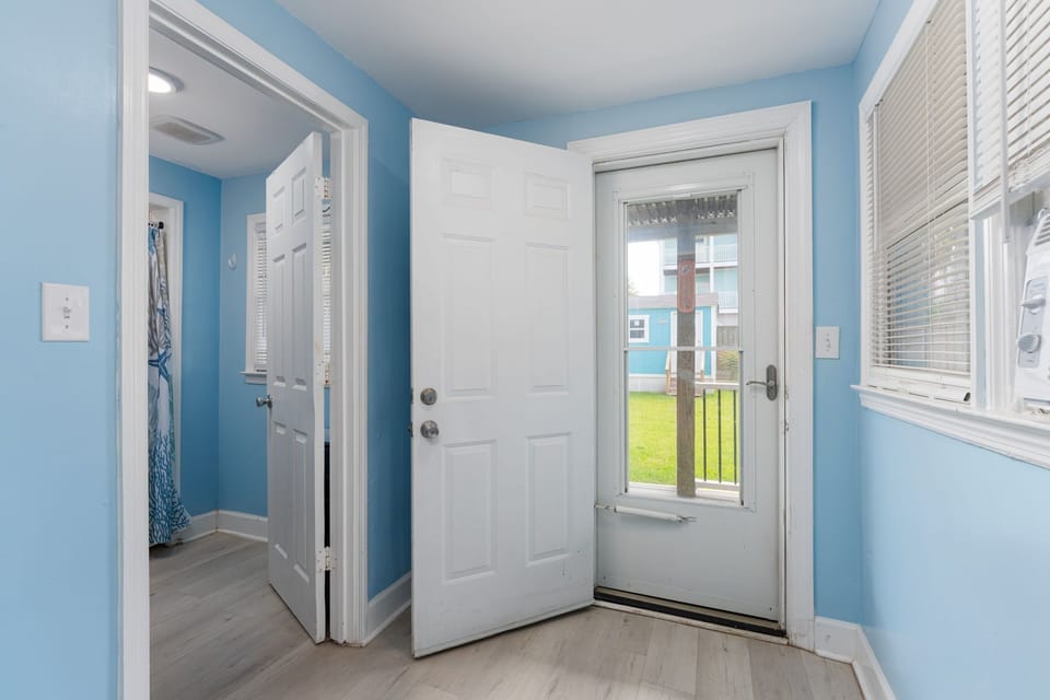 Step into your bright, breezy entryway with calming blue walls and natural light pouring through the door, welcoming you to your coastal retreat.