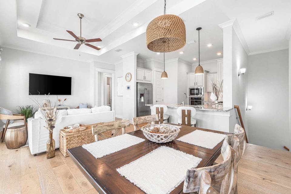 Beachy ratan lighting & flooring with view of stairs, kitchen, and living room. 
