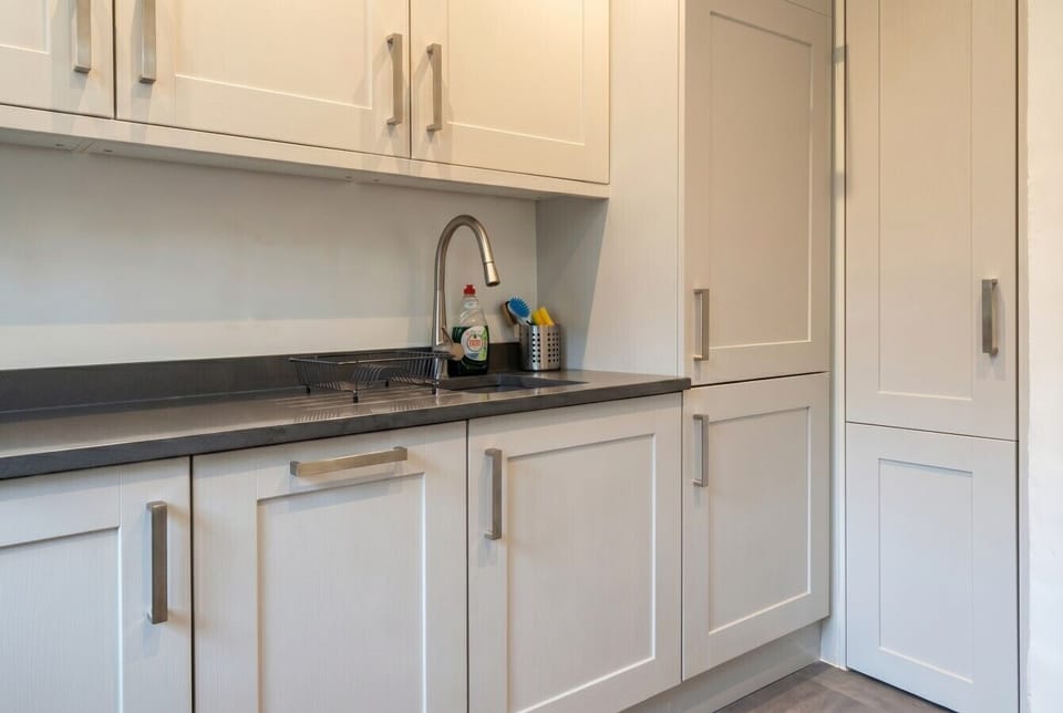Sleek cabinetry with dark stone worktops and a pull-out spray tap to cook in style.