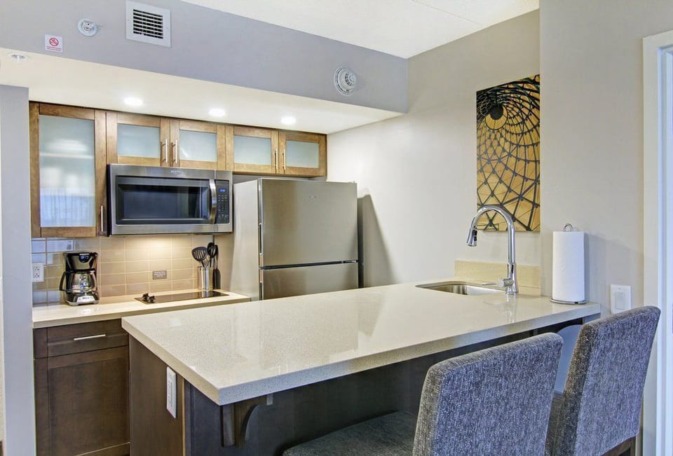 Full-size fridge, oven, stovetop, and microwave line the kitchen — bar seating for two keeps the cook company.