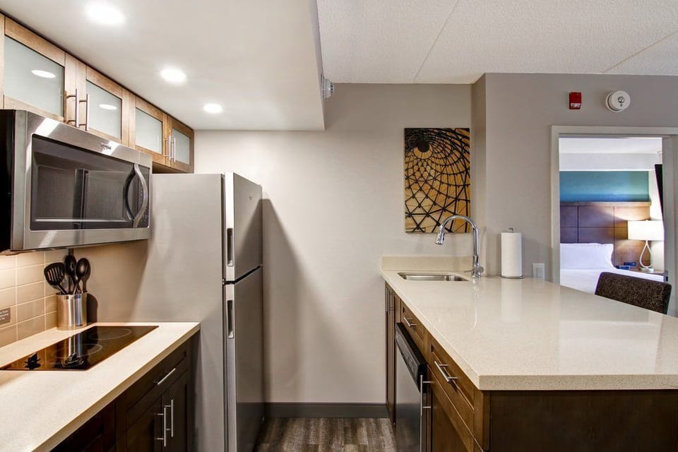 Long kitchen counter with a tiled backsplash and recessed lighting — stainless steel appliances and full cookware included for self-catering stays.