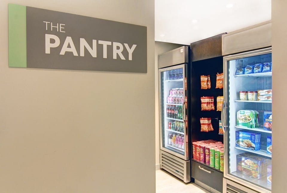 Pantry shelves stocked with everyday essentials — drinks, snacks, and grab-and-go items available 24 hours.