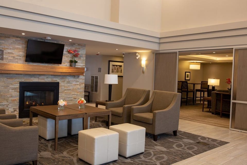 Grey armchairs and a glowing fireplace in the Great Room lounge — grab a seat before or after the Monday–Wednesday social hour.