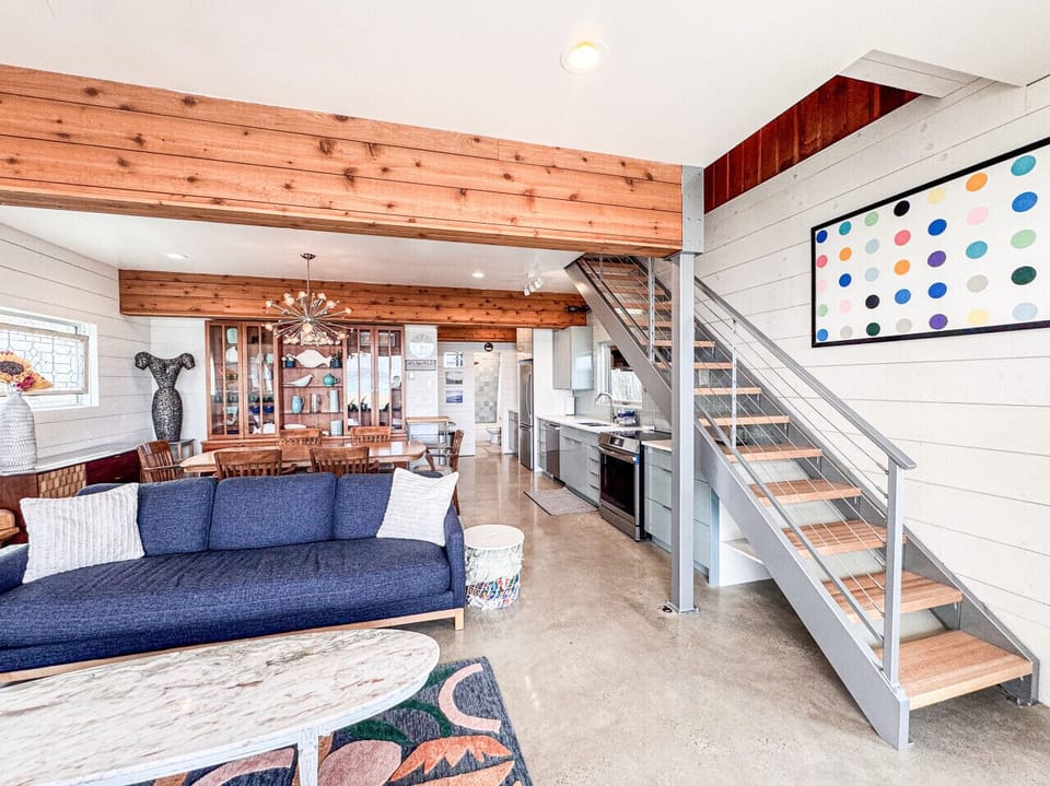 Stylish open living space with modern kitchen, dining area, and sleek staircase design