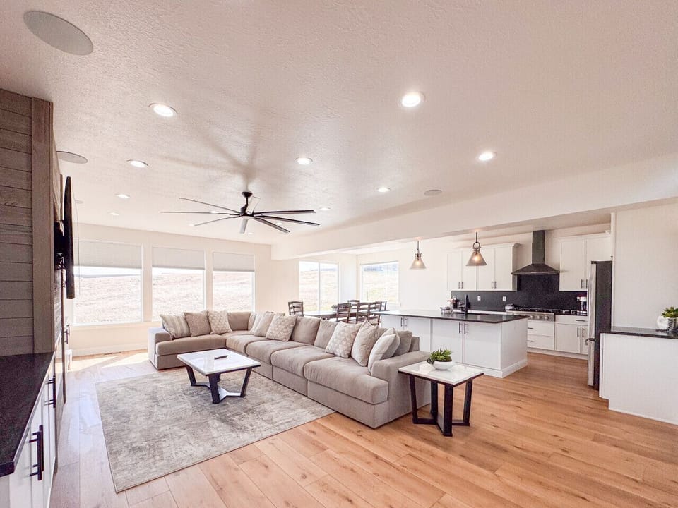 Bright open living space with sectional sofa, modern kitchen, and expansive mountain‑view windows