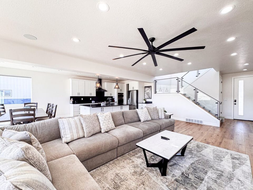 Contemporary living room with large sectional, built‑in fireplace, and stylish open staircase
