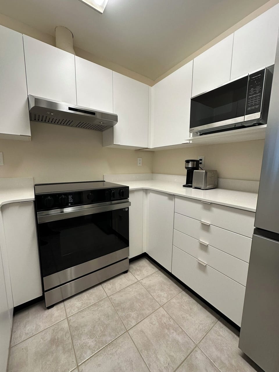 Crisp cabinetry, microwave, range hood, and clean prep surfaces