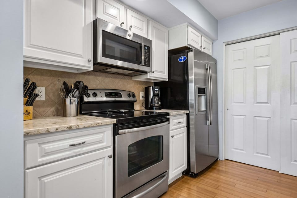 Fully stocked kitchen featuring all stainless steel appliances and 3 barstools for extra seating.