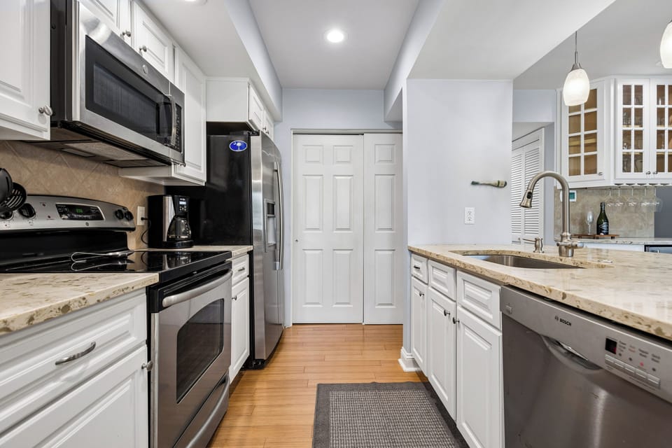 Fully stocked kitchen featuring all stainless steel appliances and 3 barstools for extra seating.