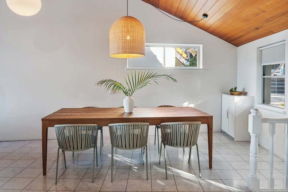 Share meals and memories at the large wooden dining table, framed by soft natural light and coastal textures.