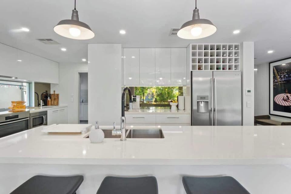 The gourmet chef's kitchen with a waterfall-edge centre island, a long breakfast bar, a butler's pantry and a suite of stainless steel appliances. 
