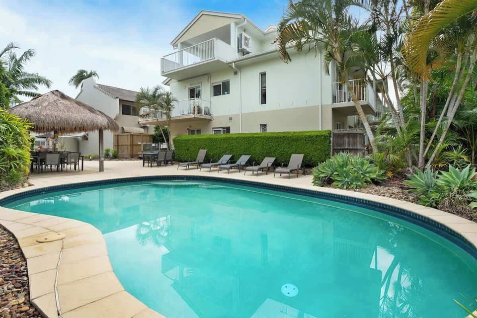 Resort style shared in-ground pool with sun loungers and cabana.